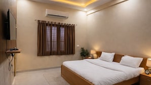 A modern bedroom with a large bed, an air conditioning unit, a ceiling fan, and a television on the wall. - Udaigarh Palace - The Heritage Hotel  (Jodhpur)
