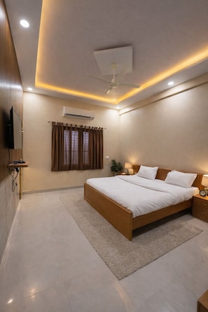 A modern bedroom with a large bed, an air conditioning unit, a ceiling fan, and a television on the wall.