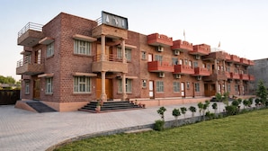 A multi-story building with a brick facade, balconies, and a paved entrance area. - Udaigarh Palace - The Heritage Hotel  (Jodhpur)