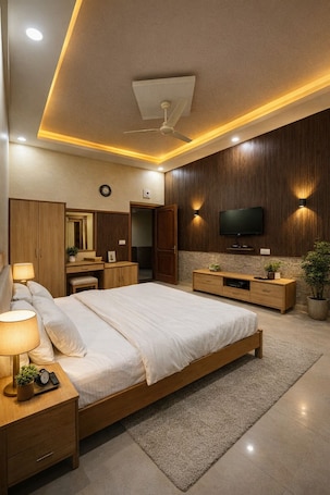 A modern bedroom with a bed, bedside tables, a TV, and a ceiling fan.. Udaigarh Palace - The Heritage Hotel