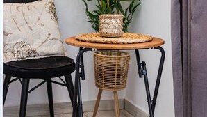 A corner room with a small round table, a chair, a potted plant, and a framed picture on the wall. - Shkodra Living | Modern 1BR Near City Center by PikHost (Shkodër)