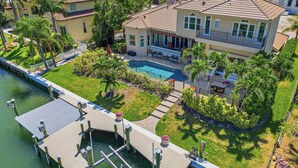 Une grande maison avec une piscine, un quai et une vue sur l’océan.
