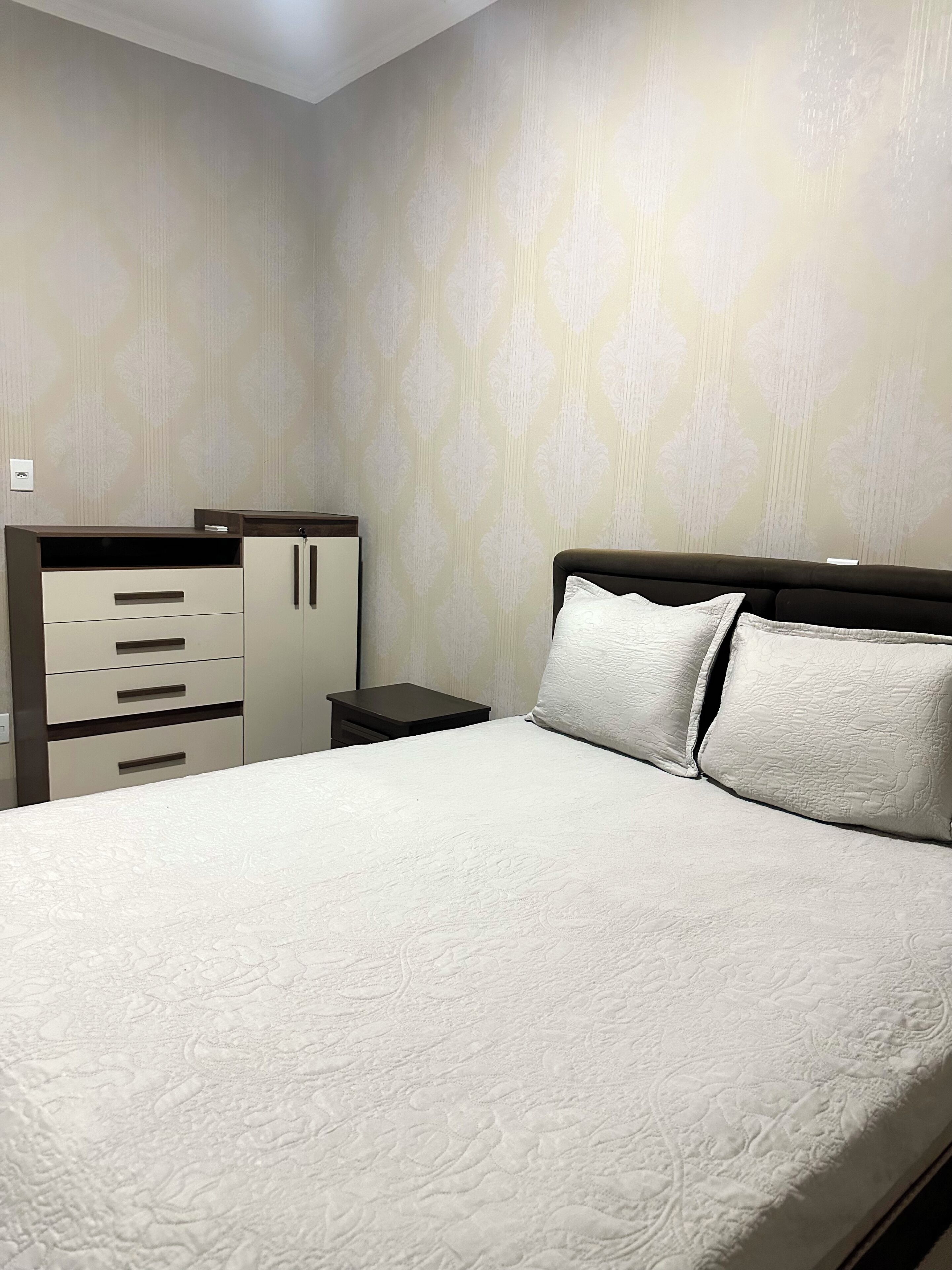 A bedroom with a bed, a nightstand, and a wardrobe.