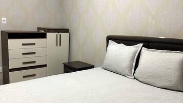 A bedroom with a bed, a nightstand, and a wardrobe.