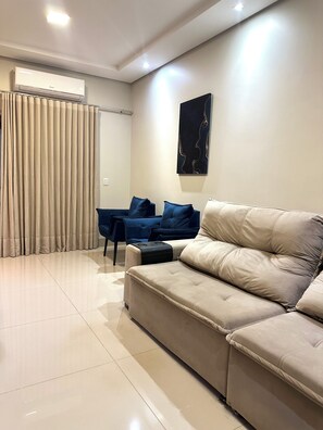 A modern living room with a beige sofa, a blue chair, and a black side table.