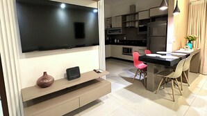 A modern kitchen with a built-in TV, a dining area with a table and chairs, and a kitchen island. - Davisis Luxo Piscina Prox Graciosa (Palmas)