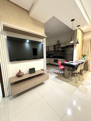 A modern kitchen with a built-in TV, a dining area with a table and chairs, and a kitchen island. - Davisis Luxo Piscina Prox Graciosa (Palmas)