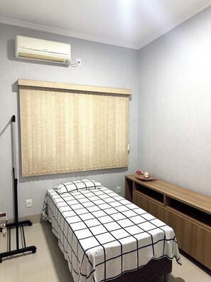A small, neatly arranged room with a bed, a desk, and an air conditioning unit. - Davisis Luxo Piscina Prox Graciosa (Palmas)