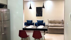 A modern kitchen with a dining area, including a refrigerator, a table with chairs, and a sofa. - Davisis Luxo Piscina Prox Graciosa (Palmas)