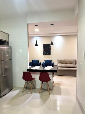 A modern kitchen with a dining area, including a refrigerator, a table with chairs, and a sofa. - Davisis Luxo Piscina Prox Graciosa (Palmas)
