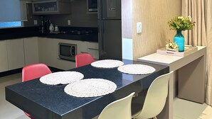 A modern kitchen with a black countertop, white chairs, and a blue vase with flowers. - Davisis Luxo Piscina Prox Graciosa (Palmas)