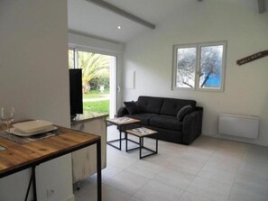 Una sala de estar moderna con un sofá, una mesa de centro, un televisor y un comedor con una mesa y sillas.