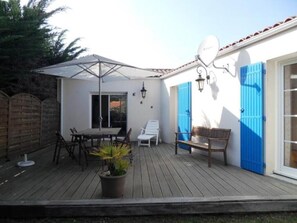 Una terraza con una mesa, sillas, un banco y una planta en maceta.