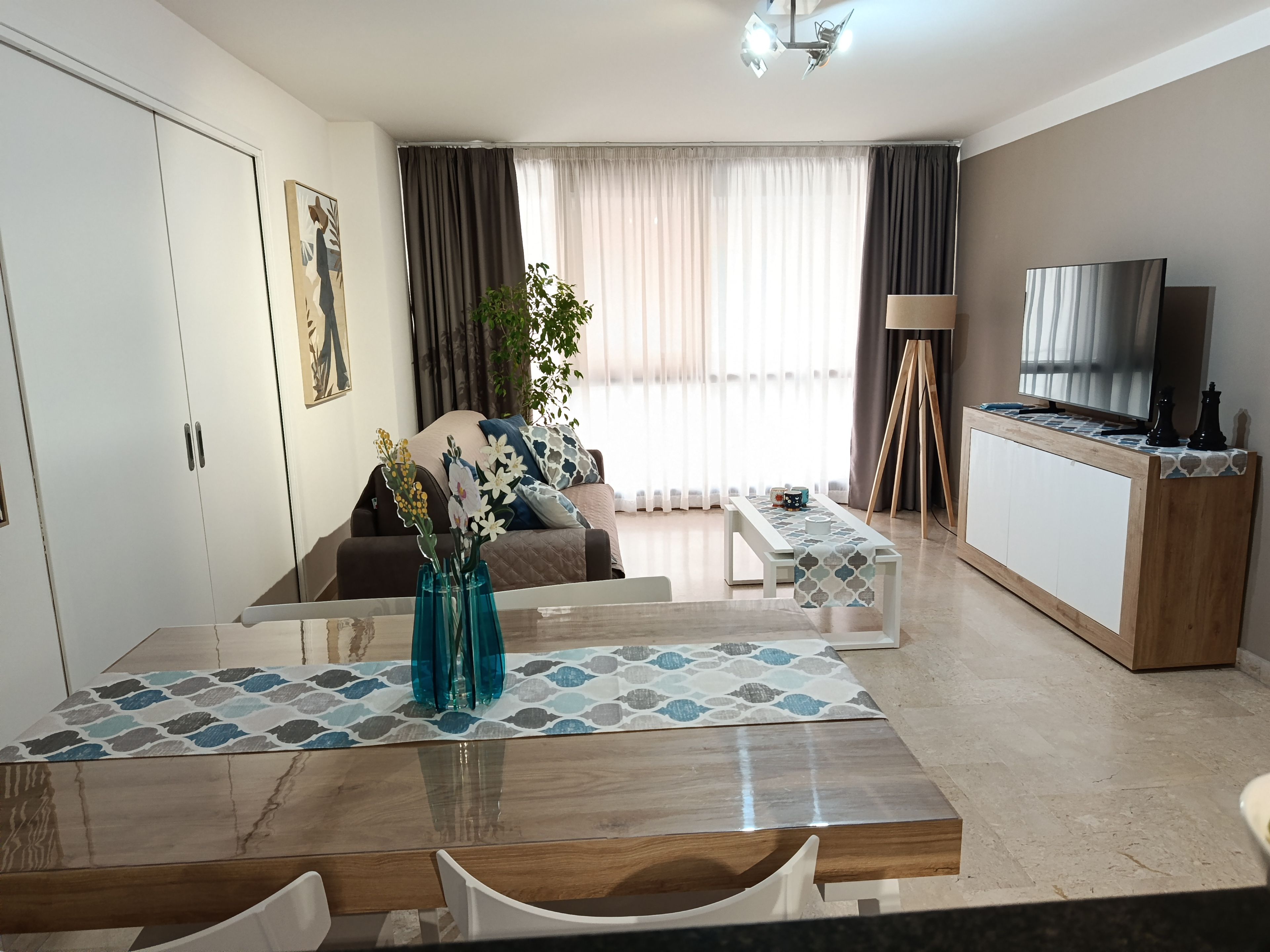 Una sala de estar moderna con una mesa de comedor, sofá y un mueble para televisión.