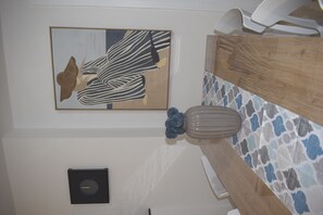 Ein Badezimmer mit Handtuchhalter, einer Wanddekoration, einer Seifenschale und einer gefliesten Spritzschutzwand.