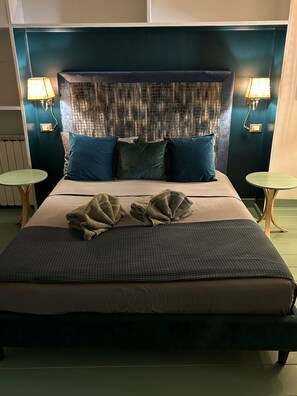 A hotel room with a large bed, two bedside tables, a headboard with a textured pattern, and two wall-mounted lamps. - Farnese Muse (Roma)