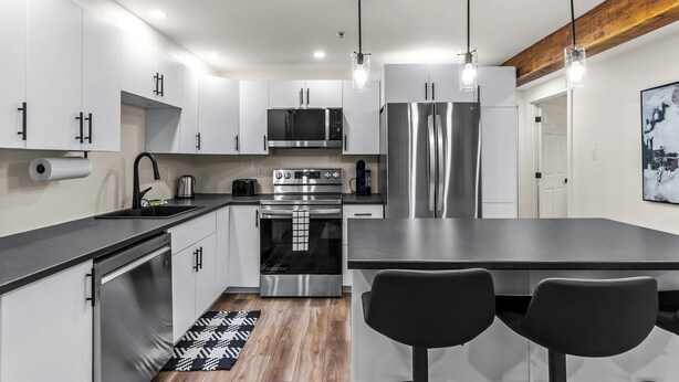 A modern kitchen with stainless steel appliances, a central island with seating, and pendant lighting.