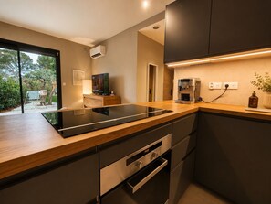 Eine moderne Küche mit Einbauherd, Kaffeemaschine und Fernseher.