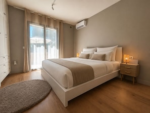 Ein Schlafzimmer mit Bett, Nachttisch, Lampe und Blick ins Freie.