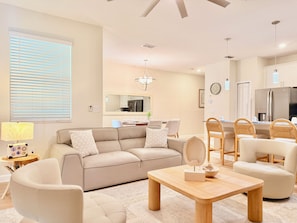 A modern living room with a sofa, chairs, a coffee table, and a dining area with a table and chairs. - Storey Lake Luxury Oasis: PS5, Private Pool, BBQ Grill, 15 min to Disney (Kissimmee)