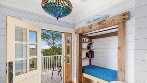 A room with a wooden bunk bed, a small table, a door leading outside, and a stained glass ceiling. - Waterfront Retreat w/ Private Pool & Unparalleled Views by Tybee Cottages (Tybee Island)