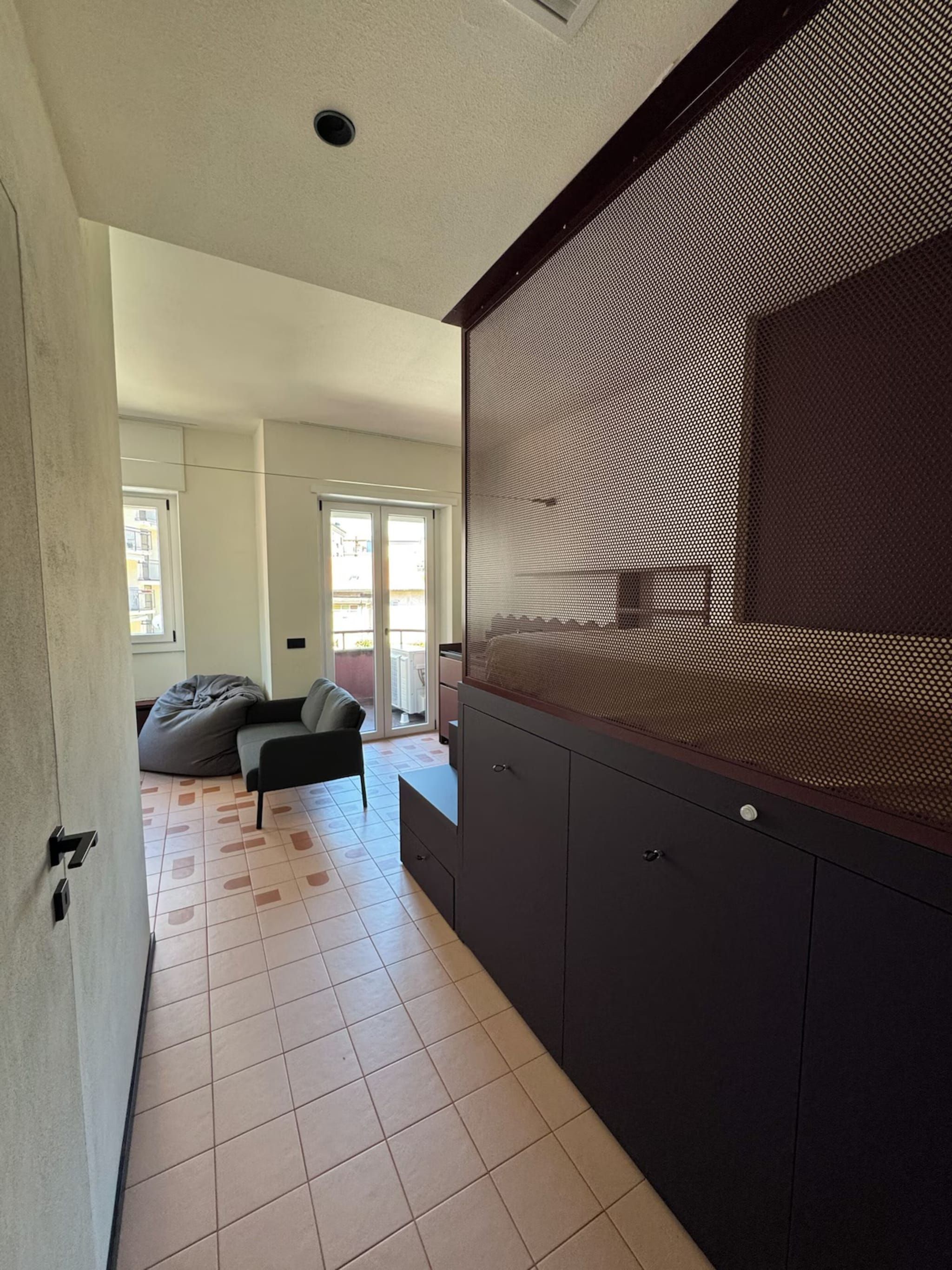 Een modern interieur met een donkere kast, een grijze bank en een behang met patroon.