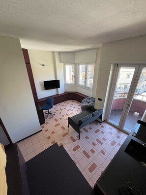 A modern living room with a sofa, a coffee table, and a TV mounted on the wall. - Studio Apartment with Balcony and Parking, 206 (Milano)