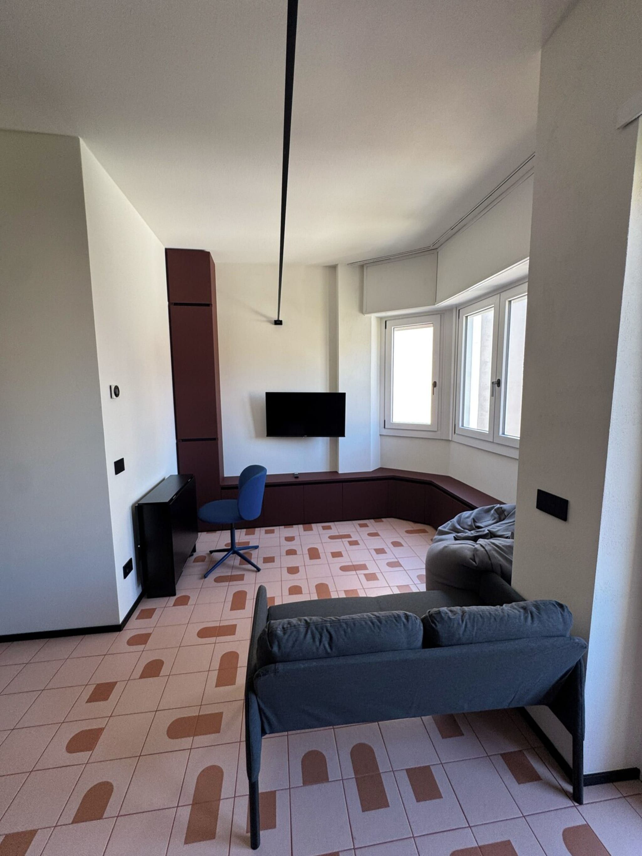 Une chambre comprenant un lit, un bureau, une chaise et un téléviseur fixé au mur.