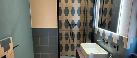 A bathroom with a shower, sink, and mirror.