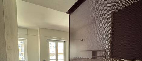 A modern interior with a dark-colored cabinet, a grey sofa, and a patterned wall.