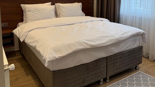 A hotel room with a large bed, two wall-mounted lights, a wooden headboard, and a window with curtains. - Armira Hotel Old City (İstanbul)