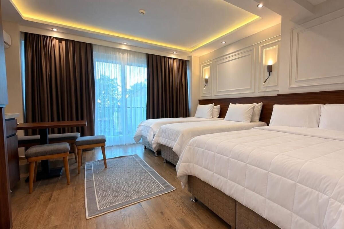 Habitación de hotel con dos camas, un escritorio y un banco.