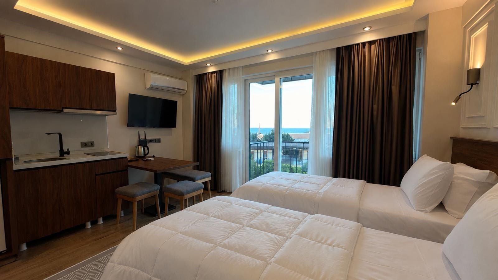 Habitación de hotel con dos camas, un escritorio, un televisor y vistas al exterior.