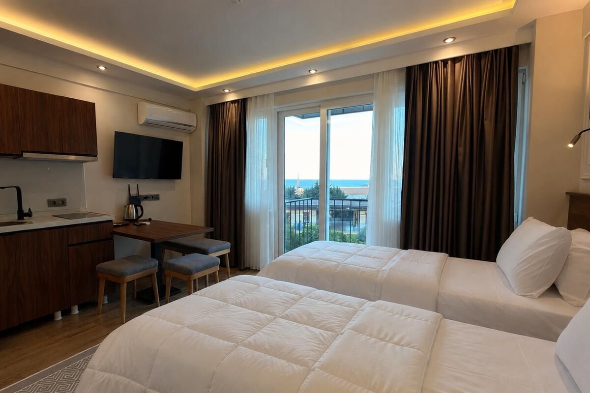 Habitación de hotel con dos camas, un escritorio, un televisor y vistas al exterior.