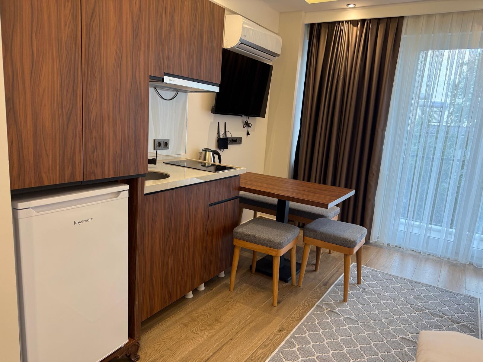 A compact kitchen with a built-in stove, a small sink, and a microwave. There is a wooden dining table with two chairs.
