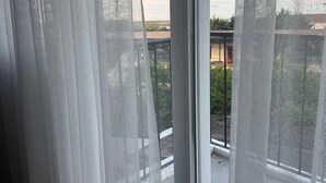 A room with sheer curtains, a large window, and a view of a building and greenery. - Armira Hotel Old City (İstanbul)