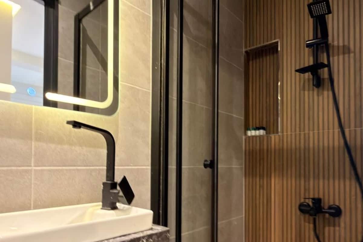 Un baño moderno con cabina de ducha de vidrio, lavamanos de mármol y pared revestida de paneles de madera.
