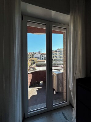 Una habitación con puerta de cristal corredera que da a un balcón con mesa y sillas.