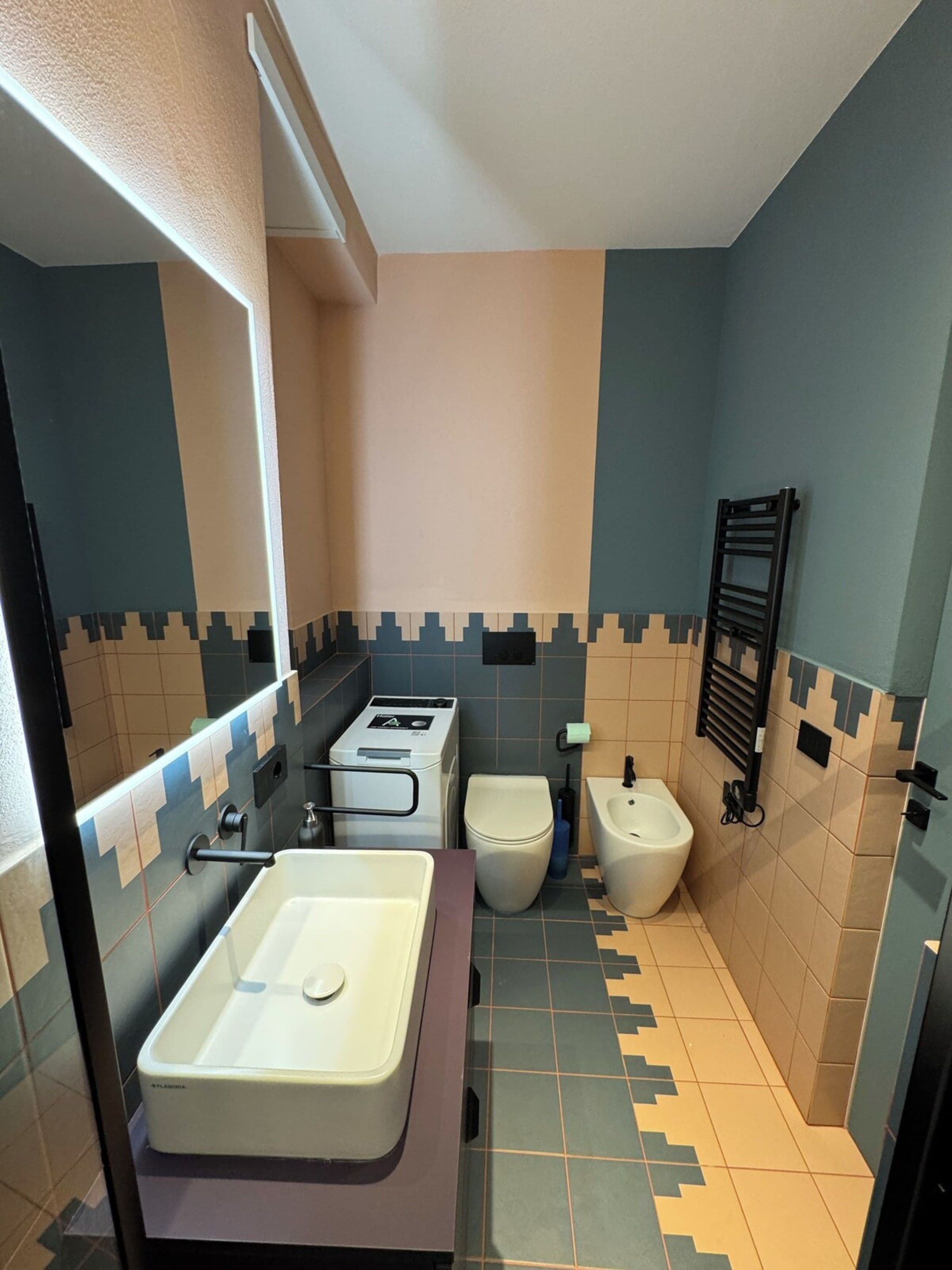 A compact bathroom with a sink, toilet, bidet, and a towel rack.