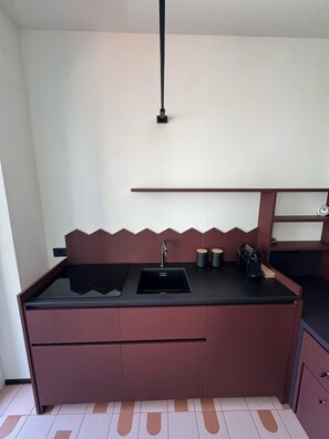 A compact kitchen with a black countertop, a single sink, and a built-in stove. - Studio apartment with balcony and parking space, 204 (Milano)