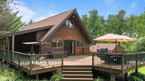 Eine Holzhütte mit einer Veranda, Sitzgelegenheiten im Freien und einem Grillbereich.