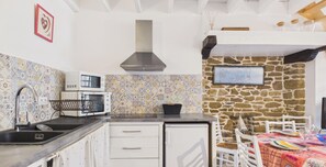 Eine kompakte Küche mit Mikrowelle, Spüle und Herd, einer Steinwand und einer Essecke mit Tisch und Stühlen.
