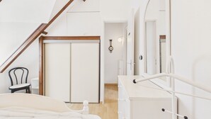Een slaapkamer met een bed, een dressoir, een stoel en een deur.