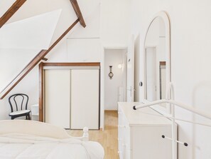 Ein Schlafzimmer mit Bett, Schminktisch, Stuhl und Tür.