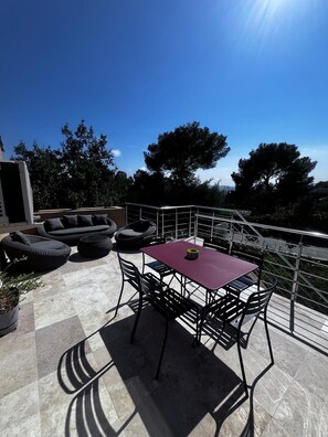 Une terrasse dotée de mobilier d’extérieur, d’une table et d’une rambarde.