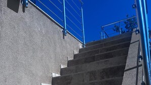 En trappa av sten som leder utomhus upp till en byggnads entré, med metallräcken på sidorna.