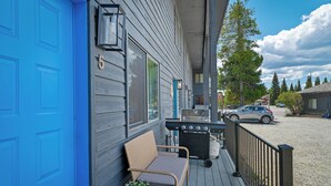 En veranda med grill, stol og blå dør.