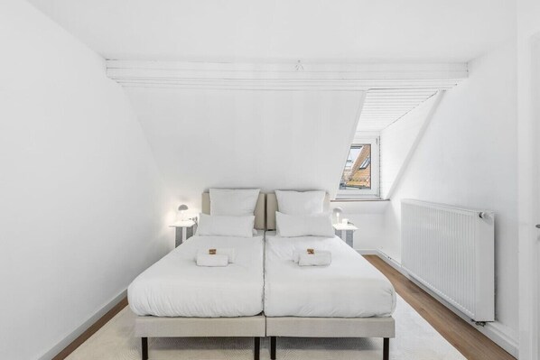 Ein Schlafzimmer mit einem großen Bett, zwei Nachttischen, einer Heizung und einem Oberlicht.