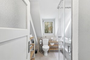 Ein kleines, modernes Badezimmer mit Toilette, Fenster und Duschbereich.
