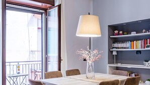 Een eetgedeelte met een tafel, stoelen, een lamp en een boekenkast.